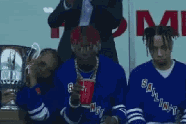 a group of young men are sitting next to each other .