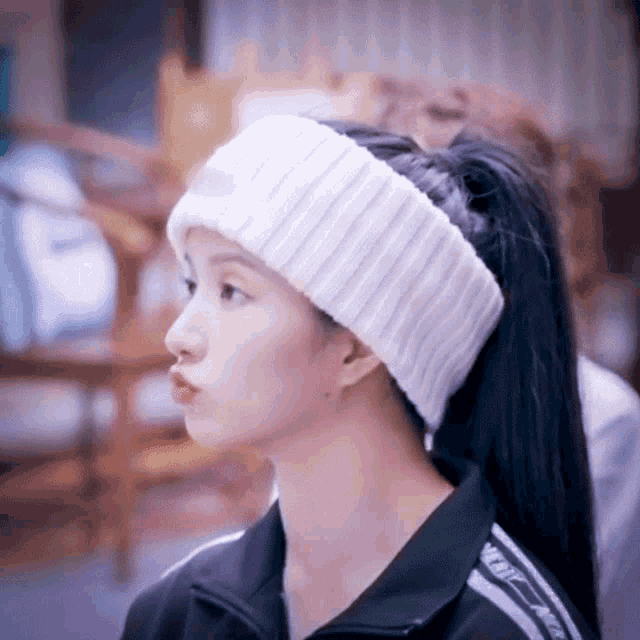 a woman wearing a white headband and a black jacket with the word nike on the sleeves