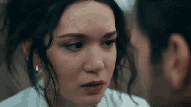 a close up of a woman 's face with a man looking at her .