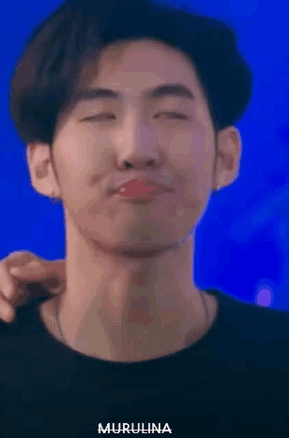 a close up of a man making a face with his eyes closed and his hand on his neck .