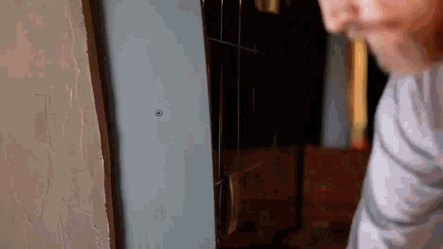 a man is standing next to a wall with a screw in it and looking at it .