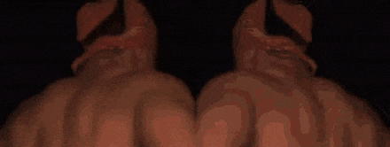 two shirtless men wearing red bandanas are smiling in the dark .