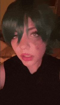 a woman with green hair and a black shirt has a bruise on her face