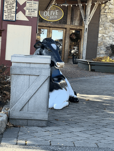 a statue of a cow sits in front of an olive basin store