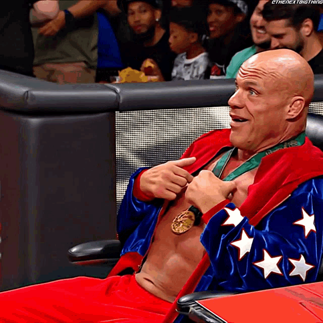 a man wearing a medal around his neck is sitting in a chair with a caption that says ' the next thing '