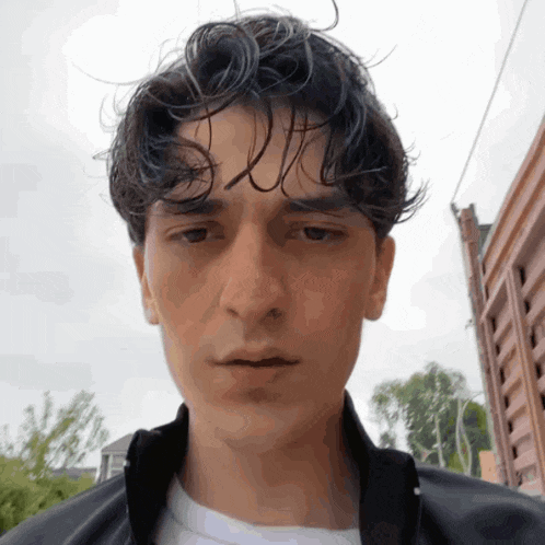 a close up of a young man 's face with a white shirt and a black jacket