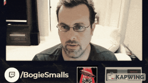 a man wearing glasses is sitting in front of a screen that says / bogiesmalls on it