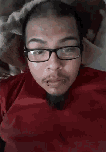 a man with glasses and a beard is making a funny face with his mouth open .