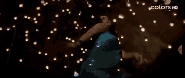 a woman in a blue dress is dancing in front of a bunch of lights with the words colors hd in the corner