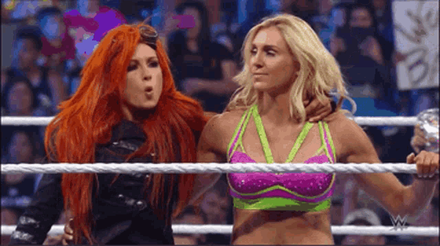 two women are standing in a wrestling ring and one has her arm around the other