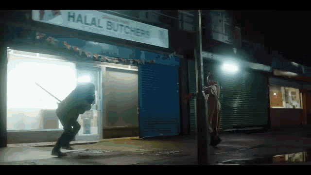 a man is standing in front of a halal butcher 's shop