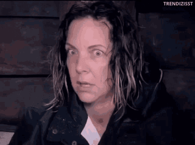 a woman with wet hair and a black jacket is making a funny face
