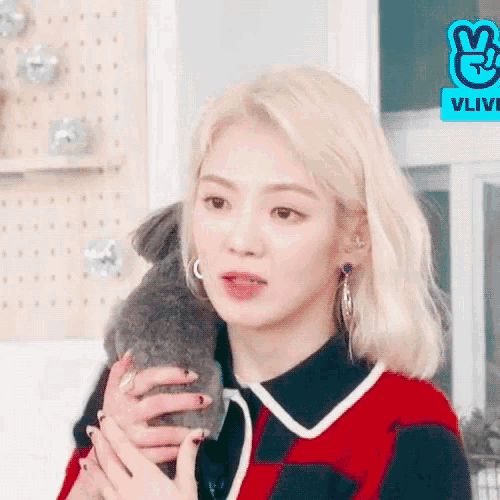 a woman with blonde hair is holding a small animal in her arms .