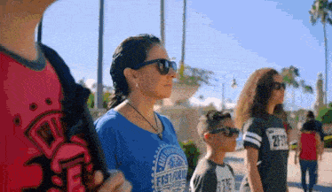 a woman wearing sunglasses and a blue shirt that says fiesta