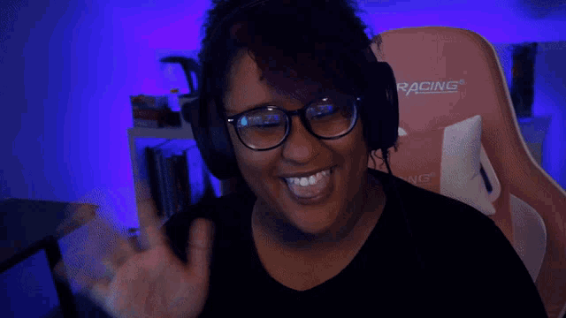 a woman wearing a pair of racing headphones waves her hand