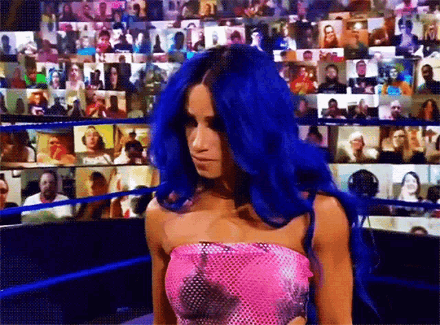 a woman with blue hair is standing in front of a crowd of people