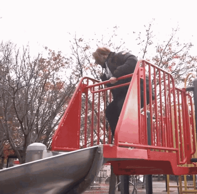 a person climbs up a red staircase at a playground