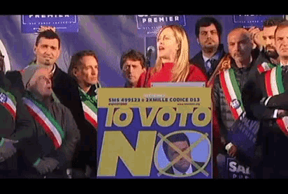 a woman stands at a podium with a sign that says iovoto no
