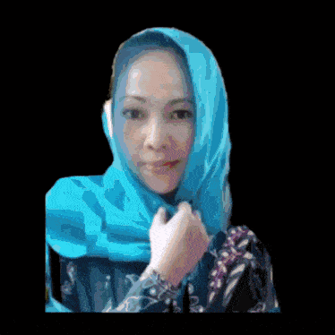 a woman with a blue scarf around her head looks at the camera