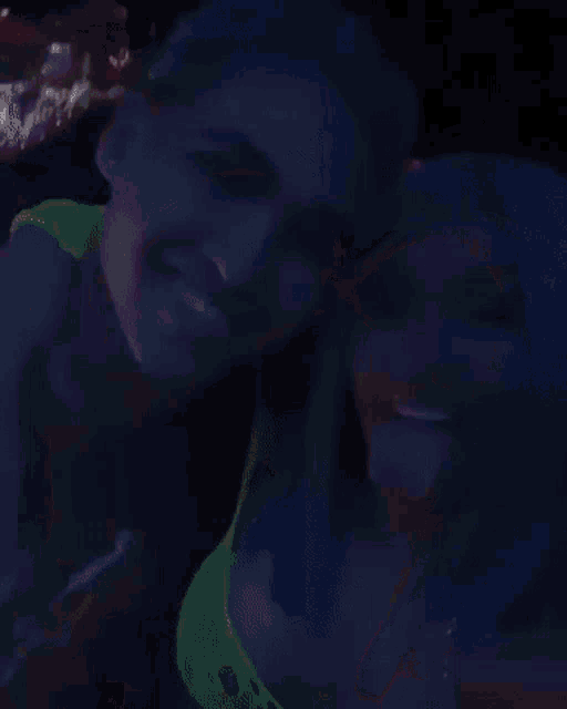 a man and a woman with blue hair are kissing each other in the dark .