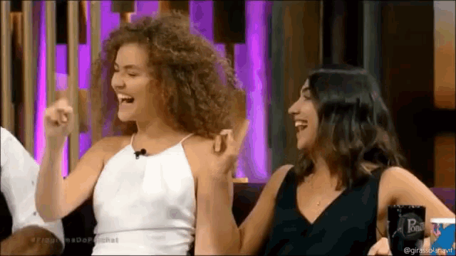 two women are sitting next to each other and one of them is wearing a black top