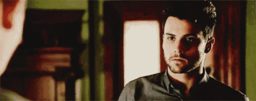 a man with a beard is standing in front of a mirror looking at himself .