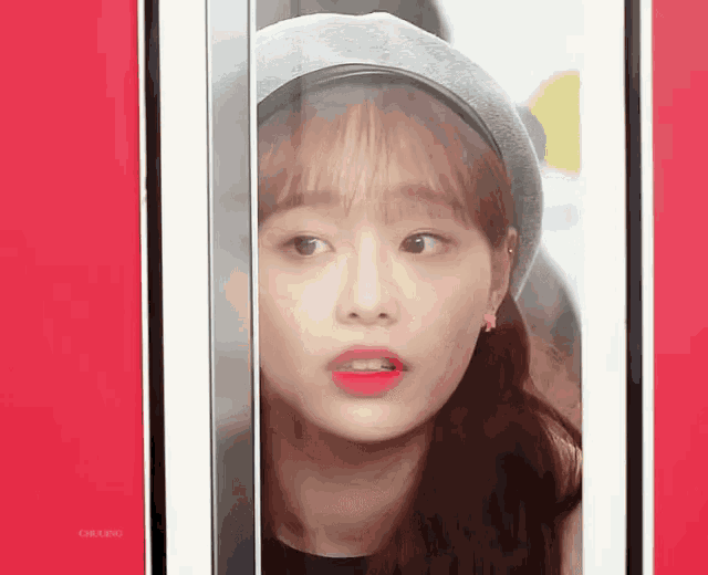 a woman wearing a beret and a headband is looking through a glass door