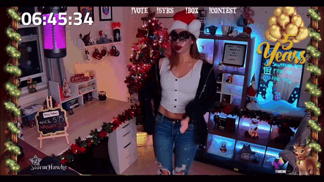 a woman in a santa hat is standing in front of a christmas tree with the time of 06:45:34