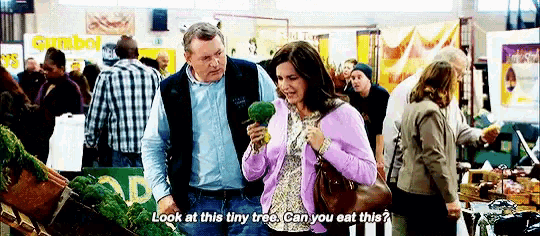 a man and a woman are looking at a tiny tree in a crowded room .