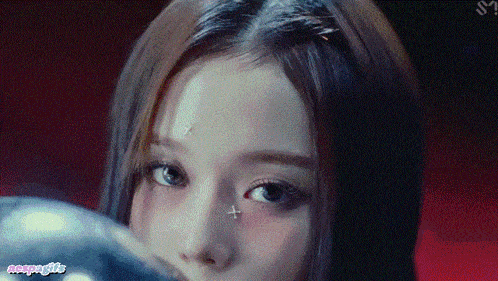 a close up of a woman 's face with a sticker on her forehead that says nemesis
