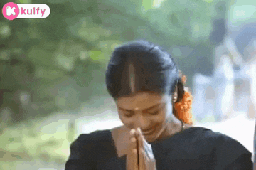 a woman is smiling and praying with her hands folded .