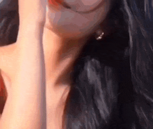 a close up of a woman 's face with long black hair covering her face with her hand .