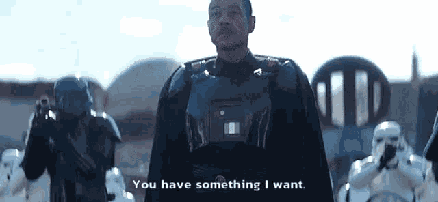 a man in a military uniform is standing in front of a group of stormtroopers .