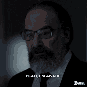 a man with glasses and a beard is saying yeah i 'm aware
