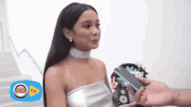 a woman in a white dress is being interviewed by a man with a microphone .