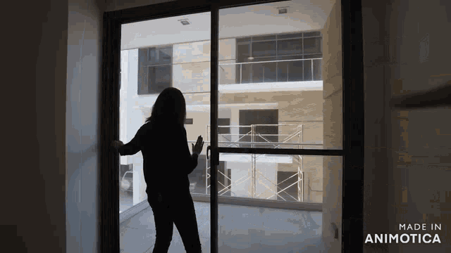 a woman is standing in front of a sliding glass door that says made in animatica
