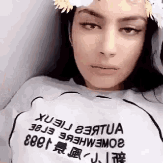 a close up of a woman wearing a flower crown and a white t-shirt .