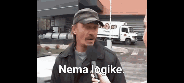 a man wearing a hat is talking into a microphone with the words nema logike written below him