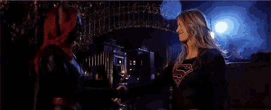 two women are standing next to each other in front of a building in the dark .