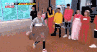 a group of people are standing in a room and a person is running in the middle of the room .