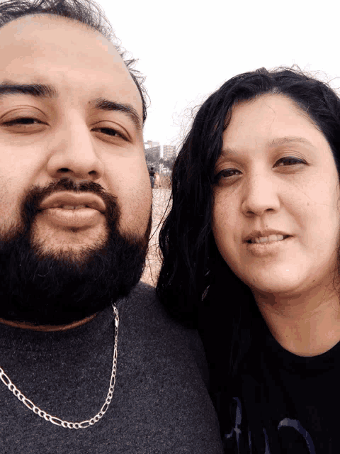 a man with a beard and a woman with long dark hair pose for a picture