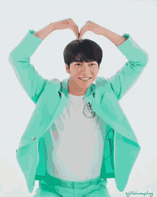 a man in a green suit is making a heart with his hands
