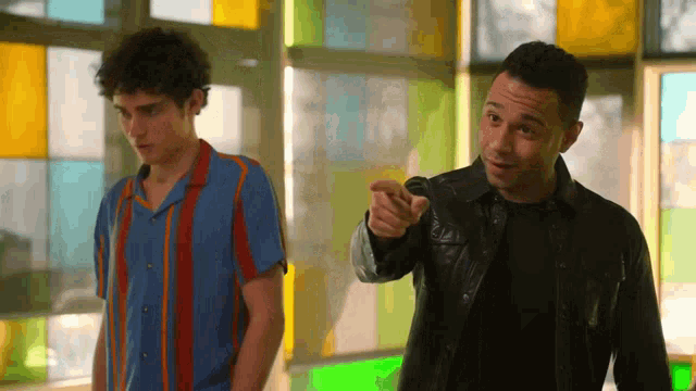 two men standing next to each other one pointing at the camera