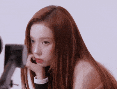 a woman with long red hair has her hand on her face