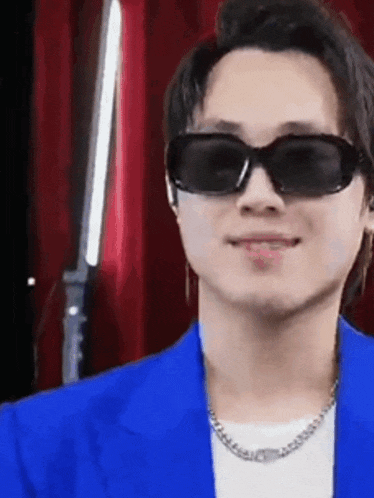 a man wearing sunglasses and a blue jacket is smiling and looking at the camera .