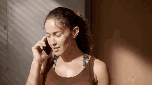 a woman is talking on a cell phone with a ctv logo in the background