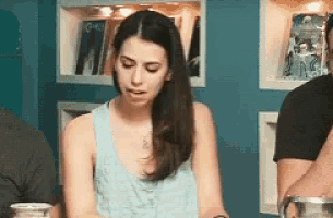 a woman in a blue tank top is sitting at a table with a cup of coffee .