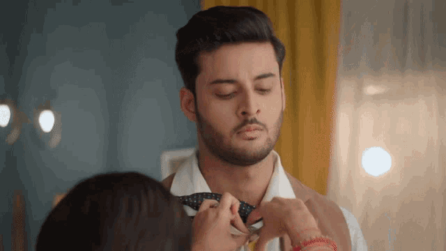 a woman adjusts a man 's bow tie with a pair of scissors