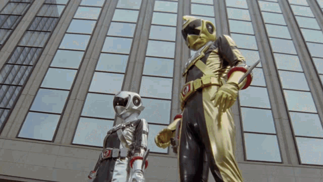 a man in a black and gold costume stands next to a woman in a white and silver costume
