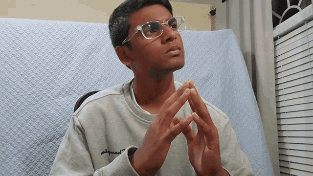a young man wearing glasses and a grey sweatshirt with the word apparel embroidered on it